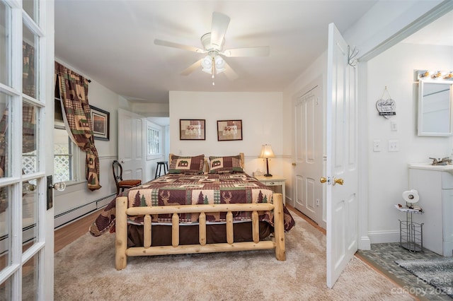 carpeted bedroom featuring ceiling fan, baseboard heating, and sink