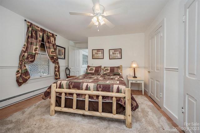 bedroom with a baseboard heating unit, ceiling fan, and hardwood / wood-style floors