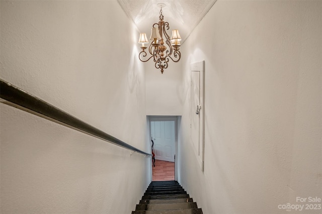 stairs with a textured ceiling and an inviting chandelier