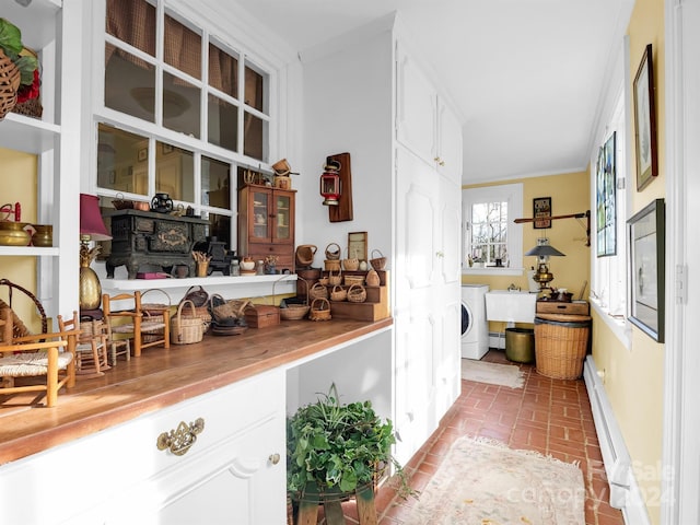 interior space with washer / clothes dryer, crown molding, baseboard heating, butcher block counters, and white cabinets