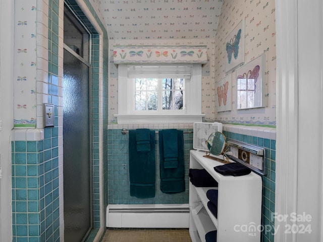 bathroom featuring a baseboard radiator, a healthy amount of sunlight, tile walls, and a shower with shower door