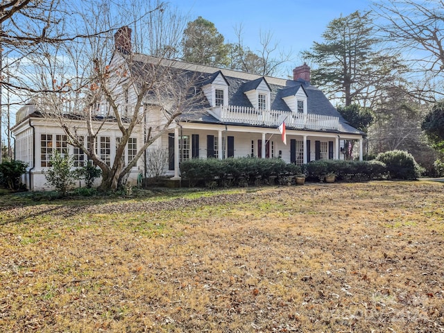 cape cod-style house featuring a front lawn and covered porch