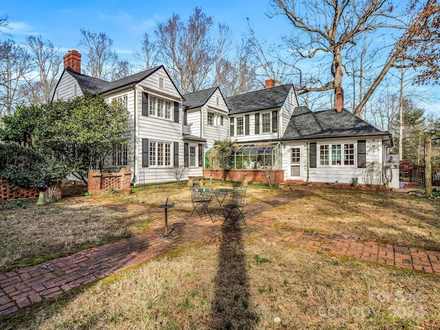 back of property featuring a sunroom and a lawn