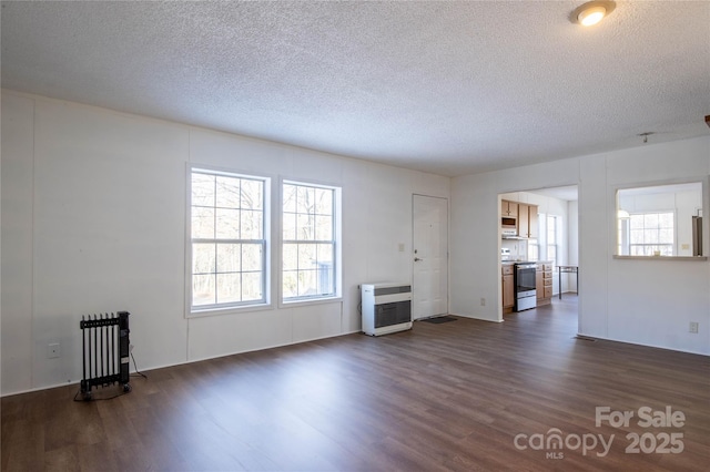 unfurnished living room with a textured ceiling, heating unit, radiator, and dark wood-type flooring