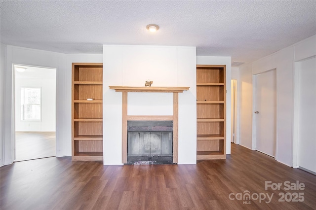 unfurnished living room featuring dark hardwood / wood-style flooring, built in features, and a textured ceiling