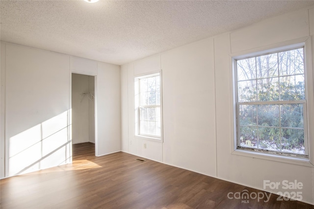 unfurnished room featuring hardwood / wood-style flooring, a textured ceiling, and a wealth of natural light