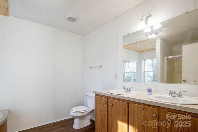 bathroom featuring vanity, hardwood / wood-style flooring, toilet, a textured ceiling, and walk in shower