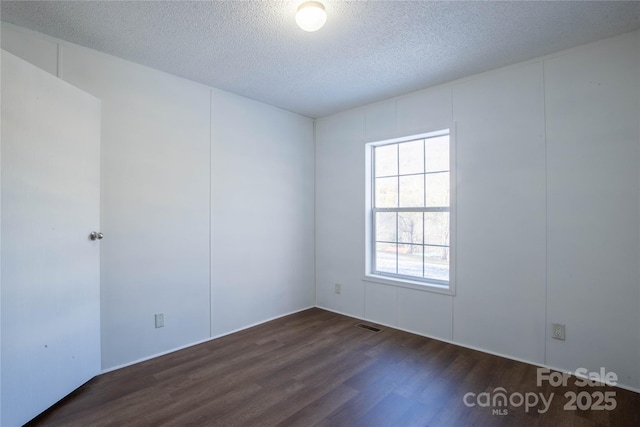 unfurnished room featuring a textured ceiling and dark wood-type flooring