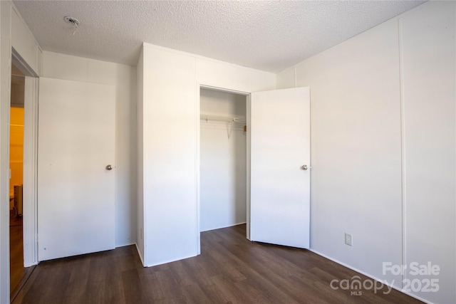 unfurnished bedroom featuring a closet, dark hardwood / wood-style flooring, and a textured ceiling