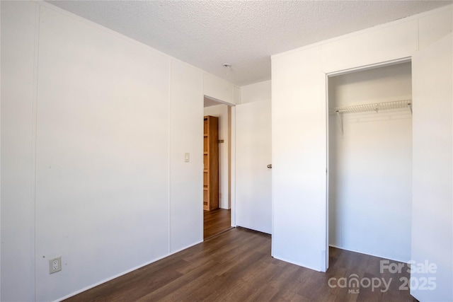 unfurnished bedroom with dark hardwood / wood-style flooring, a textured ceiling, and a closet