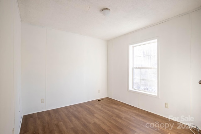 empty room with wood-type flooring and a textured ceiling