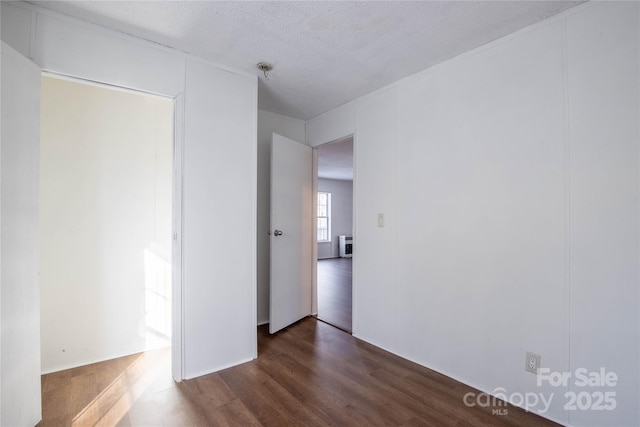 unfurnished room with dark hardwood / wood-style flooring and a textured ceiling