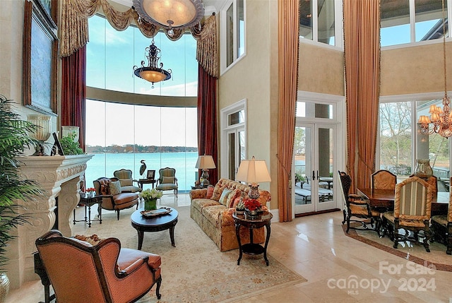 living room featuring a water view, a healthy amount of sunlight, a chandelier, and a high ceiling