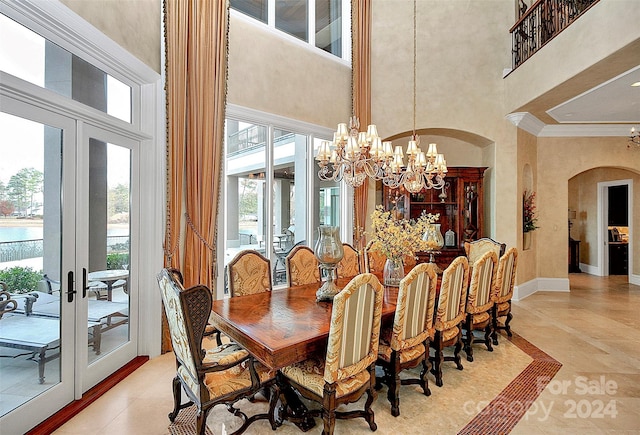 dining space featuring french doors, light tile floors, a towering ceiling, ornamental molding, and a chandelier