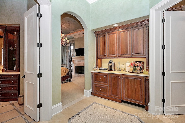 bar featuring a notable chandelier, crown molding, and light tile flooring