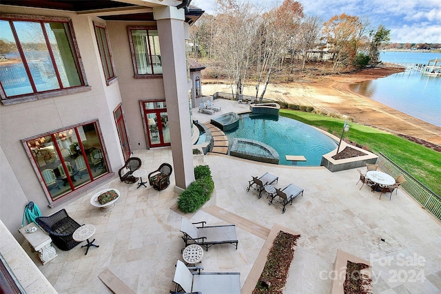 view of pool featuring a water view, a patio area, and an in ground hot tub