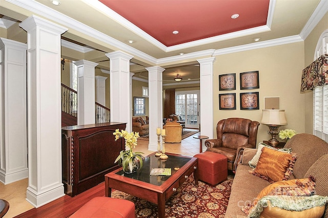 living room featuring crown molding, ornate columns, and a tray ceiling