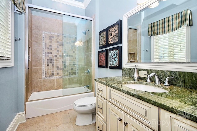 full bathroom featuring toilet, vanity, ornamental molding, tile flooring, and bath / shower combo with glass door