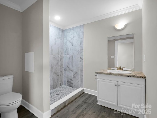 bathroom featuring hardwood / wood-style floors, vanity, toilet, tiled shower, and crown molding