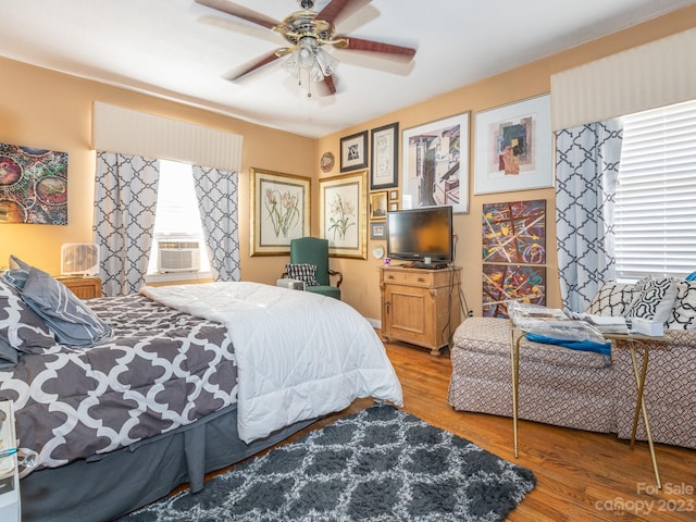 bedroom featuring ceiling fan, hardwood / wood-style floors, cooling unit, and multiple windows