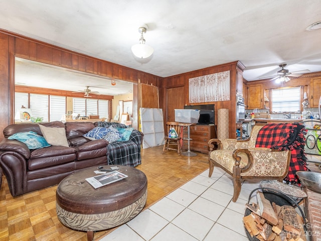 living room with wood walls, ceiling fan, and light parquet floors