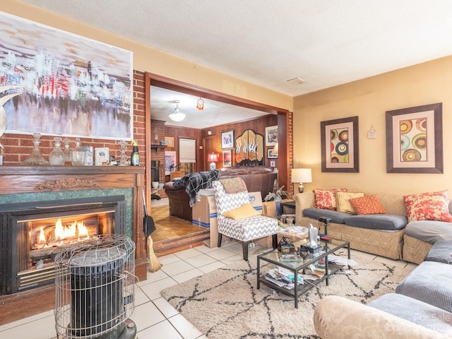 tiled living room with a fireplace, wood walls, and a textured ceiling