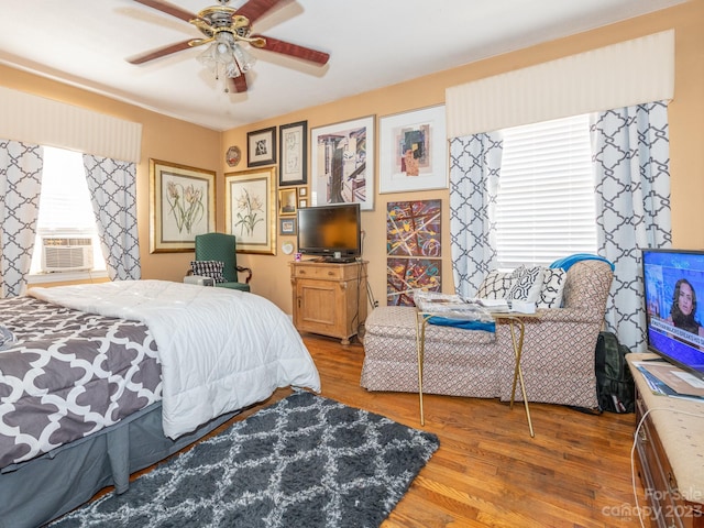 bedroom with hardwood / wood-style flooring, cooling unit, and ceiling fan