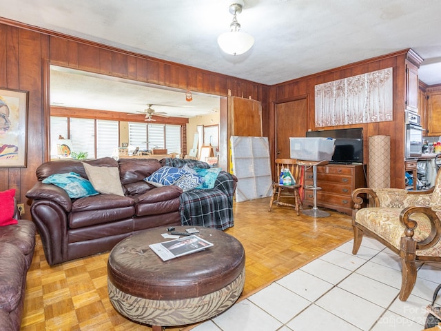 living room with ceiling fan, light parquet flooring, and wooden walls