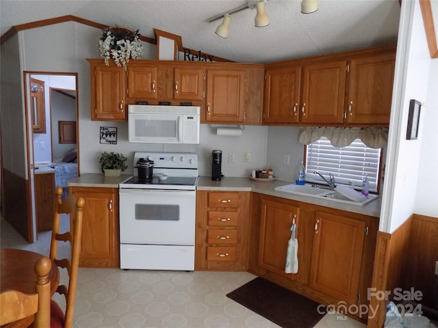 kitchen featuring track lighting, sink, white appliances, a textured ceiling, and lofted ceiling