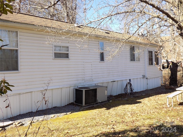 view of side of home with a yard and central AC