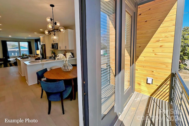 exterior space with a notable chandelier, light wood-type flooring, and wood walls