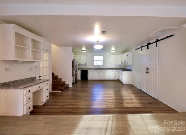 kitchen with dark hardwood / wood-style floors, a barn door, white cabinetry, and stainless steel fridge