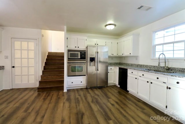 kitchen featuring light stone countertops, white cabinetry, dark wood-type flooring, appliances with stainless steel finishes, and sink