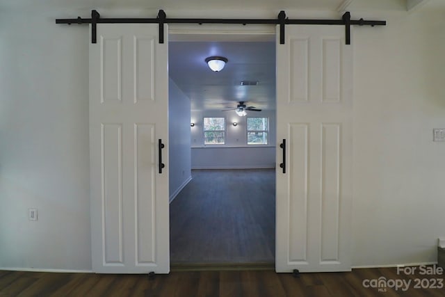 corridor featuring a barn door and dark wood-type flooring