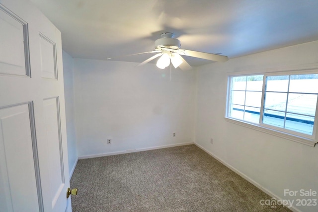 empty room featuring ceiling fan and dark carpet