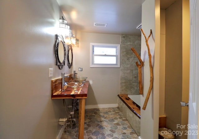 bathroom featuring tile flooring, vanity, and a tile shower