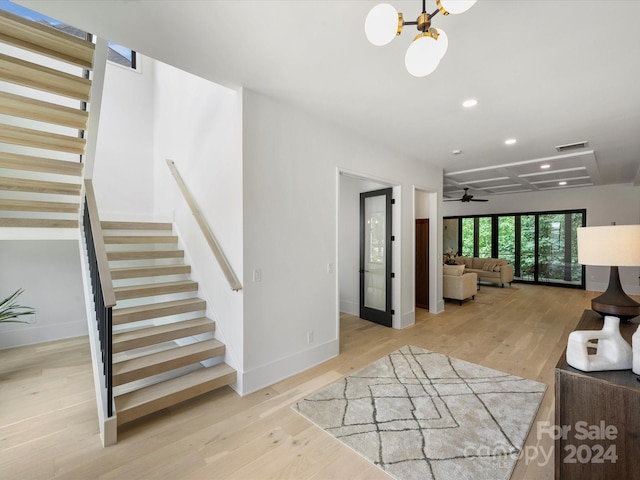 interior space featuring light wood-type flooring and ceiling fan with notable chandelier