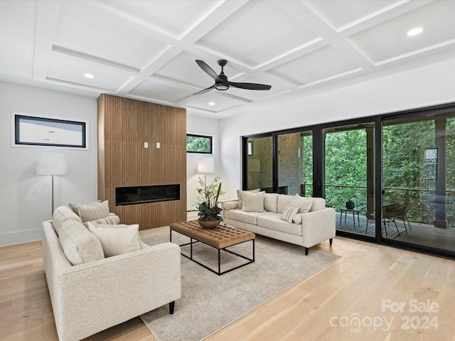 living room with a fireplace, coffered ceiling, ceiling fan, and light wood-type flooring