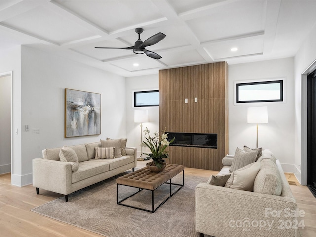 living room featuring light hardwood / wood-style floors, coffered ceiling, ceiling fan, and a large fireplace