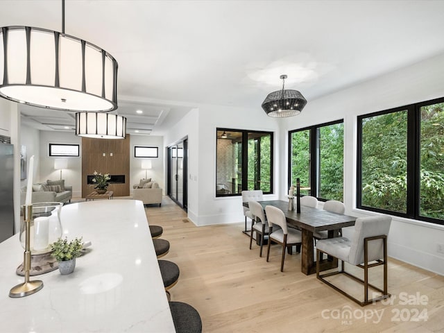 dining space with a raised ceiling, light wood-type flooring, and a chandelier