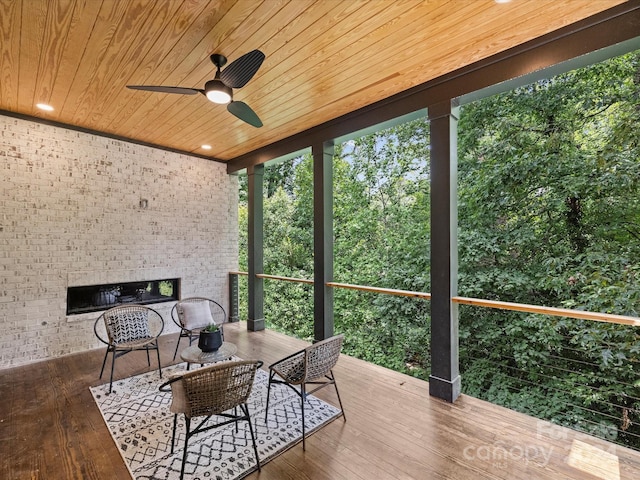 sunroom with ceiling fan, exterior fireplace, and wooden ceiling