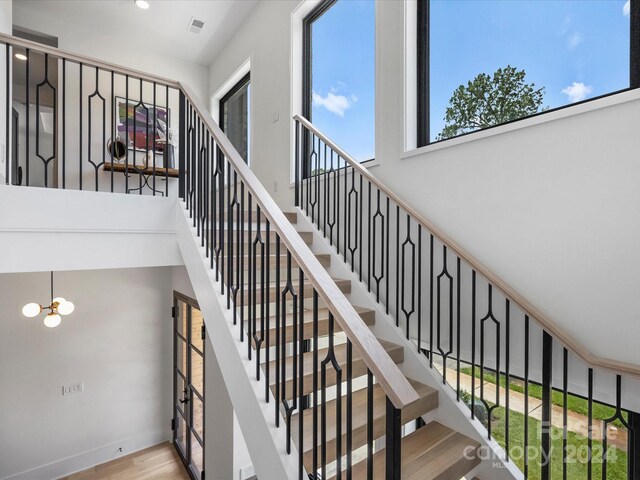 staircase with a chandelier and light hardwood / wood-style floors