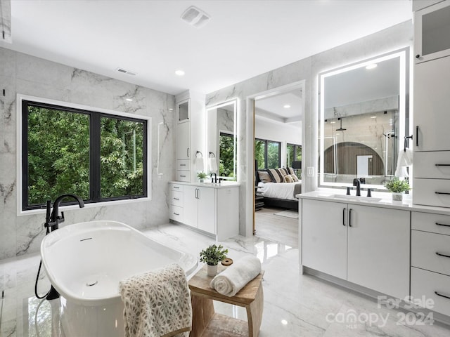 bathroom with vanity, tile walls, and a bath