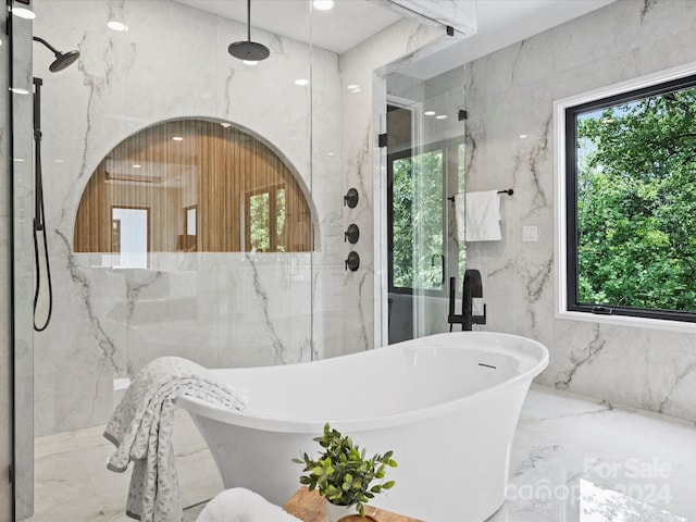 bathroom with shower with separate bathtub, tile walls, and a healthy amount of sunlight