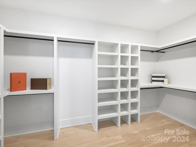 walk in closet featuring light wood-type flooring and built in desk