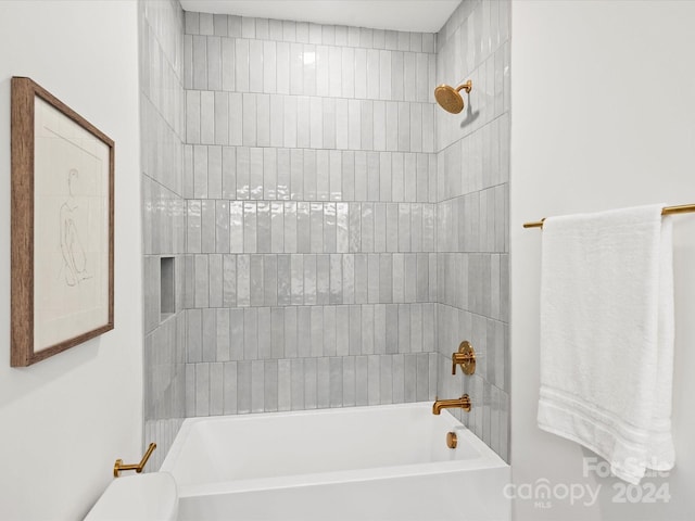 bathroom with tiled shower / bath combo and toilet