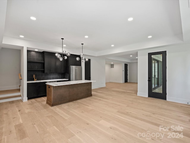 kitchen featuring high end fridge, pendant lighting, a kitchen island, light hardwood / wood-style flooring, and backsplash