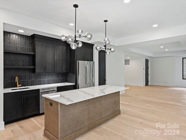 kitchen with decorative backsplash, stainless steel appliances, sink, and light wood-type flooring