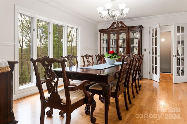 dining space featuring ornamental molding, a notable chandelier, french doors, and light hardwood / wood-style floors