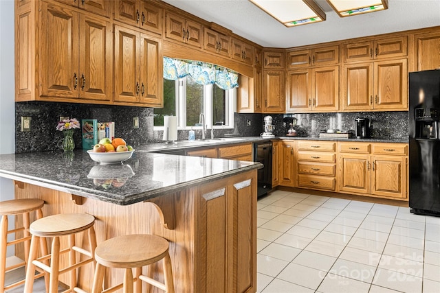 kitchen featuring kitchen peninsula, a kitchen breakfast bar, black fridge with ice dispenser, and tasteful backsplash